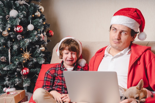 Pai e filho chorando com laptop no Natal