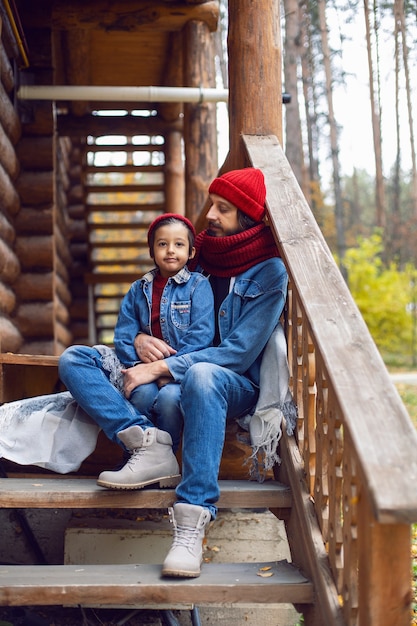 Pai e filho com chapéus vermelhos e lenços de malha estão sentados