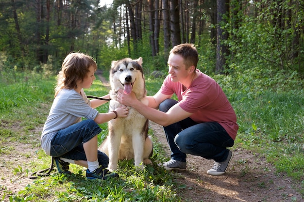 Pai e filho com seu cão malamute em uma caminhada na floresta