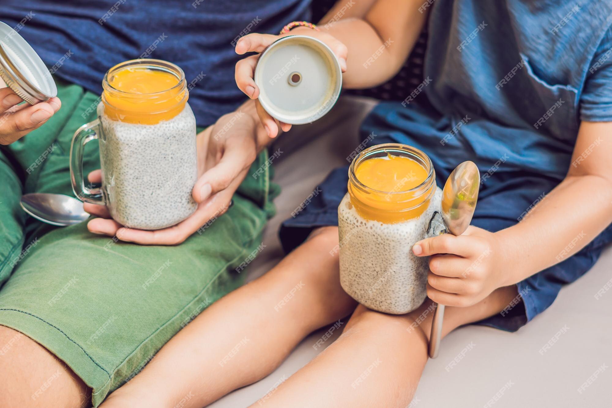 Pai e filho comem sobremesa com sementes de chia e mangas à beira da  piscina pela manhã. alimentação saudável, comida vegetariana, dieta e  conceito de pessoas.