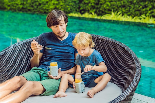 Pai e filho comem sobremesa com sementes de chia e mangas à beira