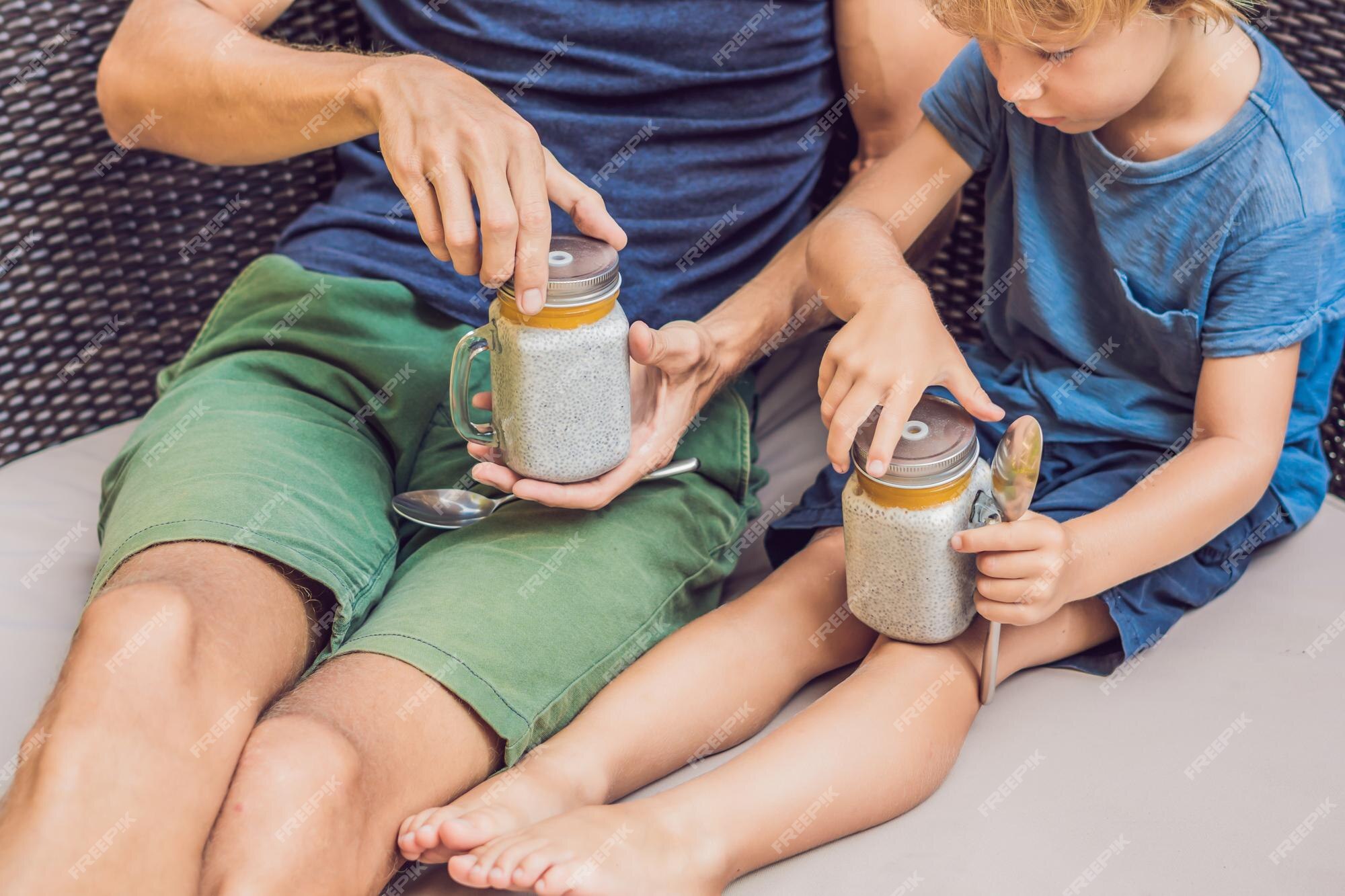 Pai e filho comem sobremesa com sementes de chia e mangas à beira da  piscina pela manhã. alimentação saudável, comida vegetariana, dieta e  conceito de pessoas.