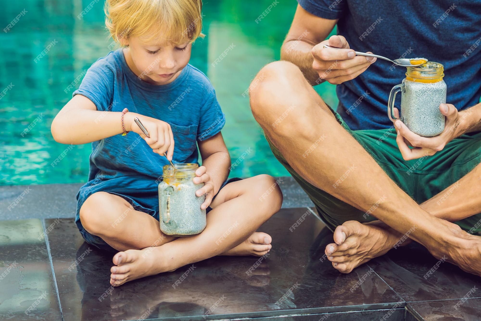 Pai e filho comem sobremesa com sementes de chia e mangas à beira