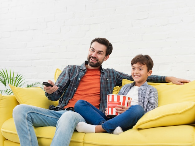 Foto pai e filho comendo pipoca e assistindo tv