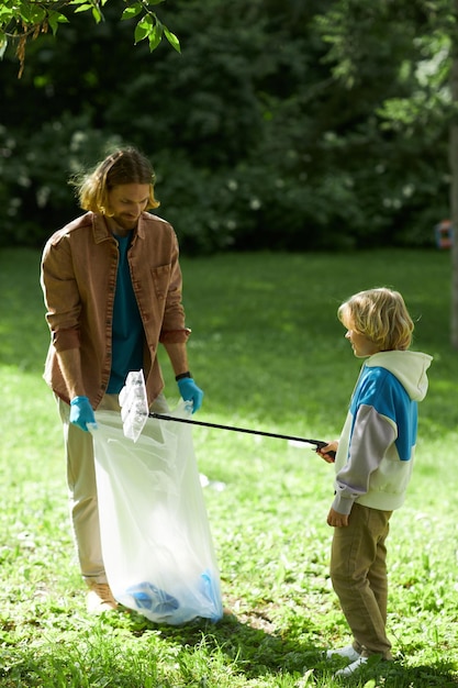 Pai e filho como voluntários ecológicos catando lixo no parque de verão