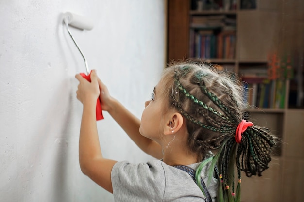 Pai e filho consertando o quarto juntos e pintando a parede juntos