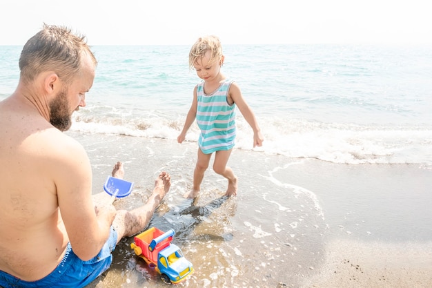 Foto pai e filho correndo juntos em direção ao oceano durante as férias de verão