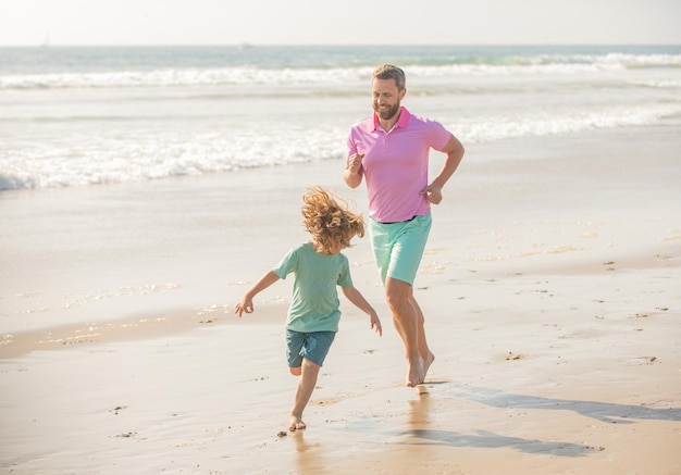 Pai e filho correndo na praia de manhã. fim de semana de viagem em família e férias.