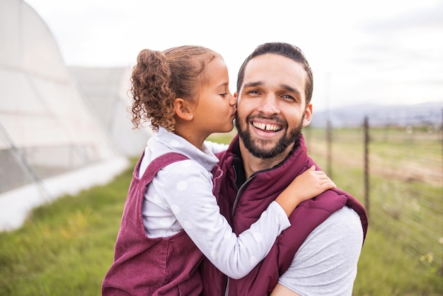 Foto pai e filho da fazenda beijam a bochecha do pai por união e carinho em terras agrícolas sustentáveis pai e filha sendo afetuosos com amor e cuidado na agricultura e no campo verde orgânico