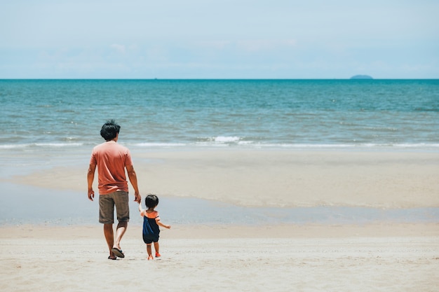 Pai e filho de família asiática feliz relaxam e passear juntos na praia durante o dia na Tailândia, conceito de férias de viagens de verão