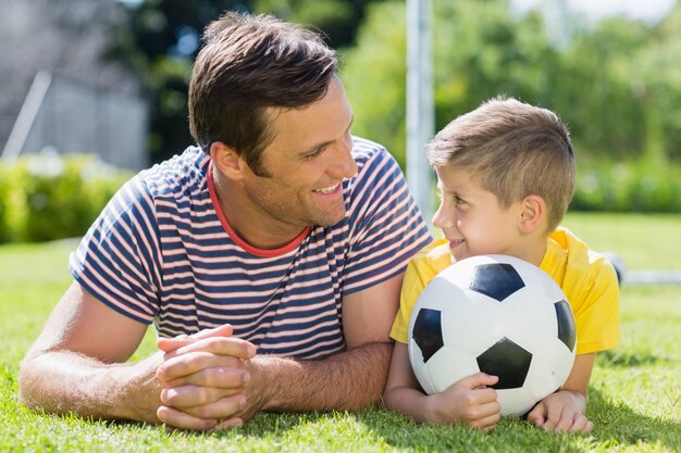 Pai e filho deitados na grama do parque