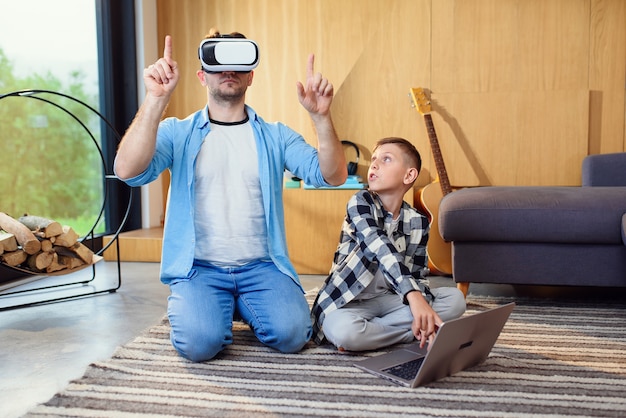 Pai e filho em fones de ouvido de realidade virtual brincando com gamepads em casa