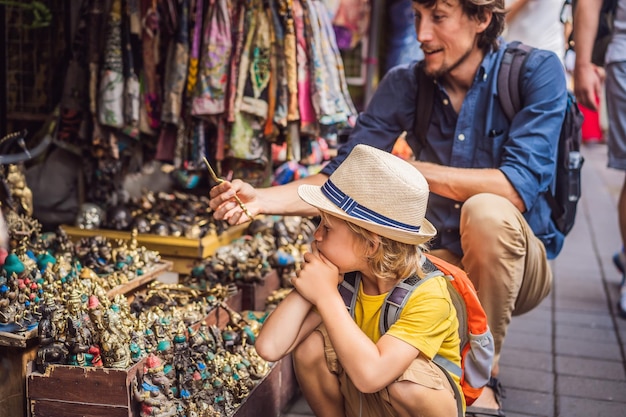 Pai e filho em um mercado em Ubud Bali Loja de souvenirs típica que vende lembranças e artesanato de Bali no famoso mercado de Ubud Indonésia Mercado balinês Lembranças de madeira e artesanato local