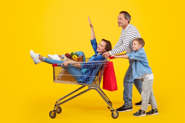 Pai e filho empurrando carrinho de compras com a mãe