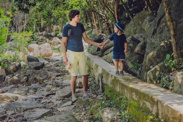 Pai e filho estão caminhando pela estrada da floresta