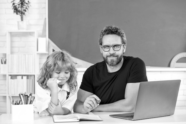 Pai e filho estudam em sala de aula com laptop escolar online