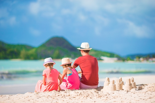 Pai e filho fazendo castelo de areia na praia tropical