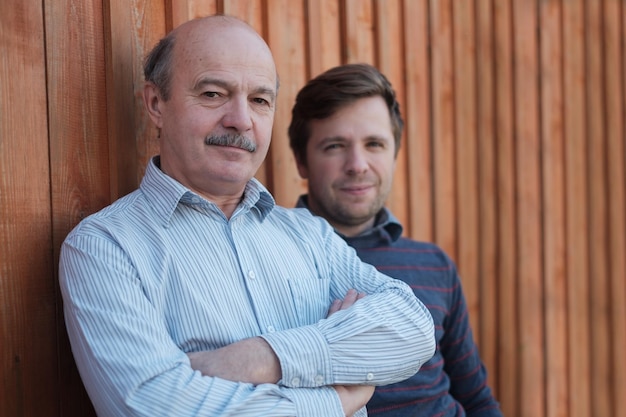 Pai e filho ficam juntos perto de fundo de madeira