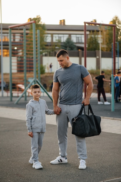 Pai e filho ficam no campo de esportes após o treino durante o pôr do sol. estilo de vida saudável.