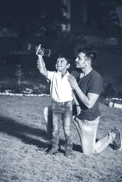 Pai e filho indianos com avião de brinquedo, ao ar livre