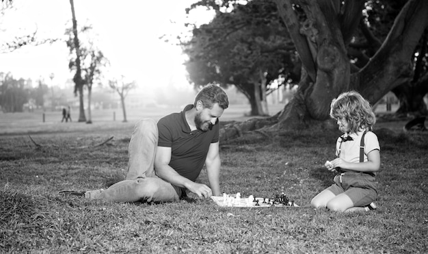 Pai e filho jogam jogo de lógica pai e filho jogando xadrez na grama no parque dia dos pais