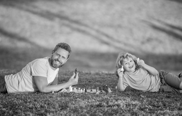 Pai e filho jogam jogo de lógica pai e filho jogando xadrez na grama no parque dia dos pais