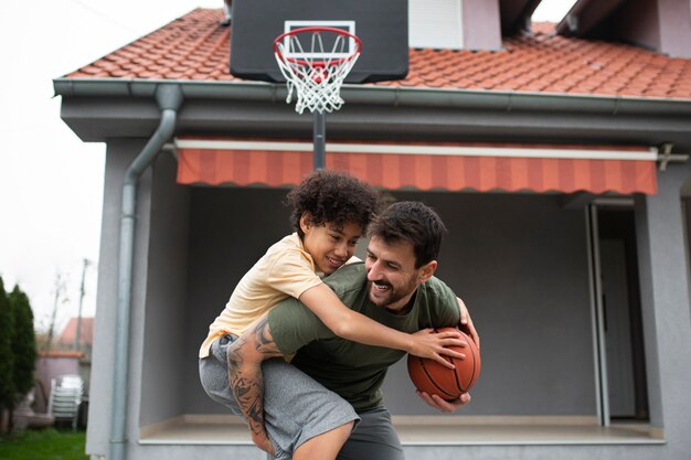 Foto pai e filho jogando basquete juntos no quintal