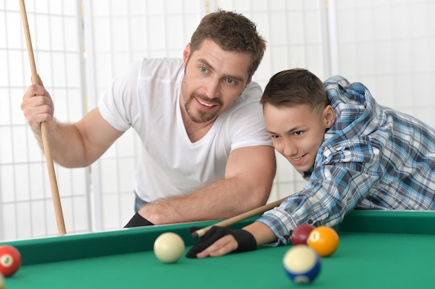 Pai e filho jogando bilhar, posando e sorrindo