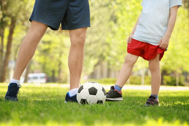 Pai e filho jogando futebol na grama verde no parque