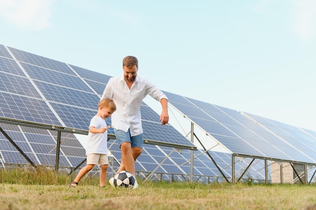 Pai e filho jogando futebol no jardim com painéis solares