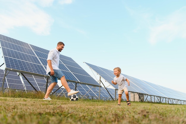 Foto pai e filho jogando futebol no jardim de painéis solares