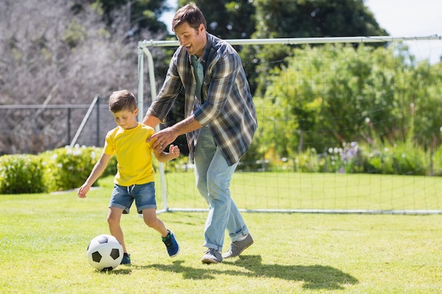 Foto pai e filho jogando futebol no parque