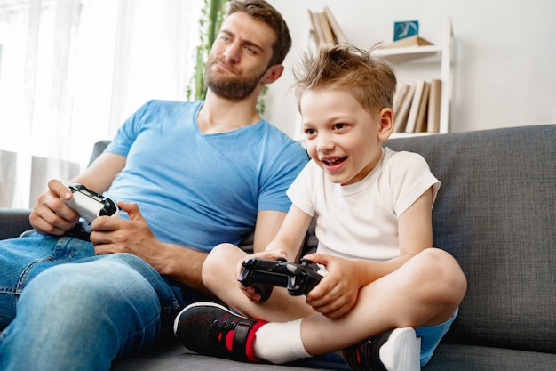 Pai e filho jogando videogame juntos no sofá em casa
