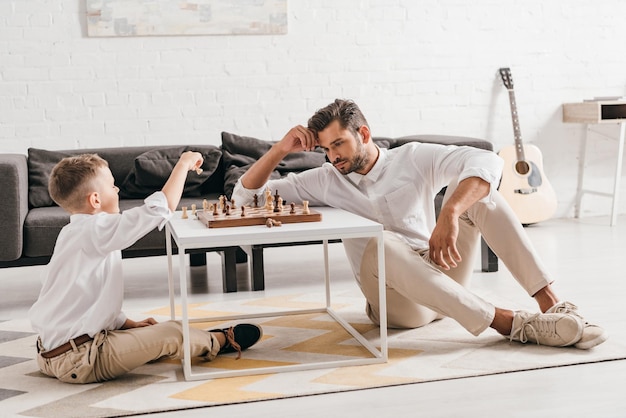 Foto pai e filho jogando xadrez juntos em casa