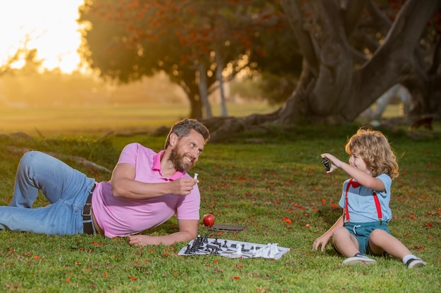 Pai e filho jogando xadrez no parque ensolarado