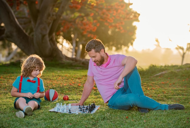 Pai e filho jogando xadrez passando tempo juntos criança ao ar livre aprendendo a jogar xadrez garotinho