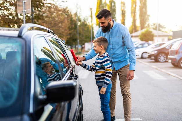 Foto pai e filho lavando o carro juntos.