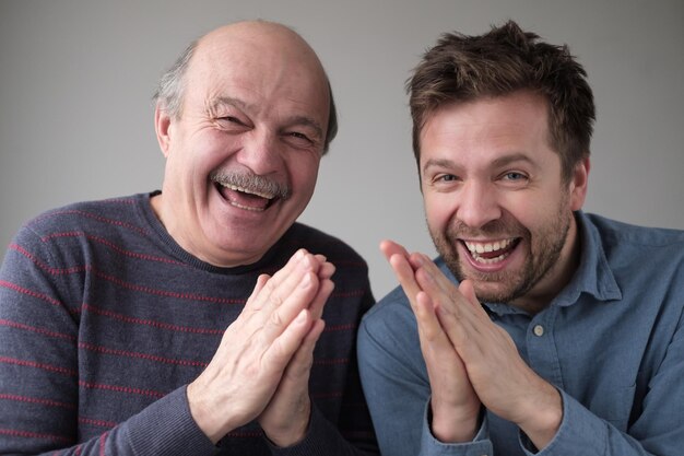 Pai e filho maduros sorrindo misteriosamente apertando as mãos planejando algo mantendo segredo