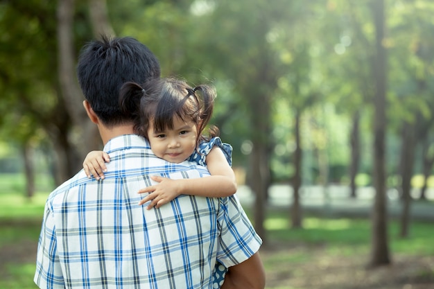 Pai e filho, menina pequena feliz descansando no ombro de seu pai no parque, efeito de filtro vintage