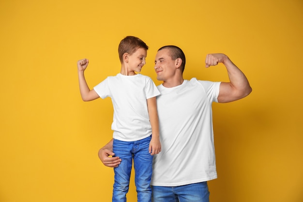 Pai e filho mostrando músculos na parede colorida