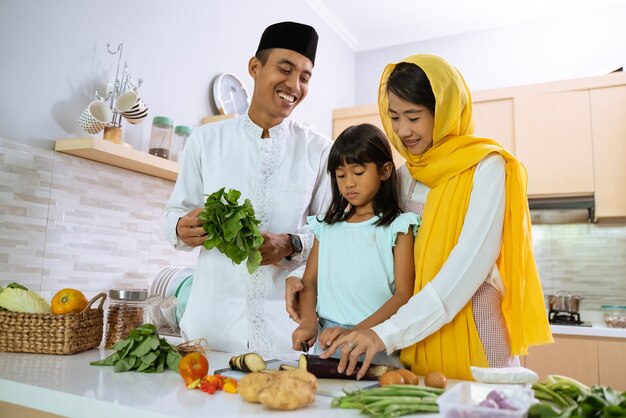 Pai e filho muçulmano cozinhando e preparando o jantar iftar juntos na cozinha durante o jejum do Ramadã