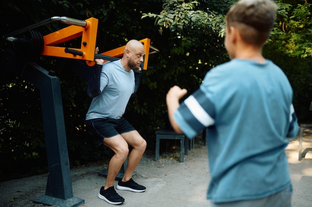 Pai e filho na máquina de exercícios, treinamento esportivo