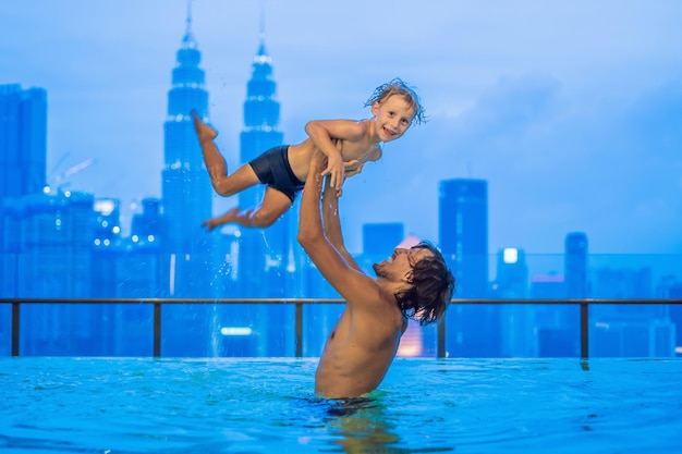 Pai e filho na piscina ao ar livre com vista da cidade no céu azul