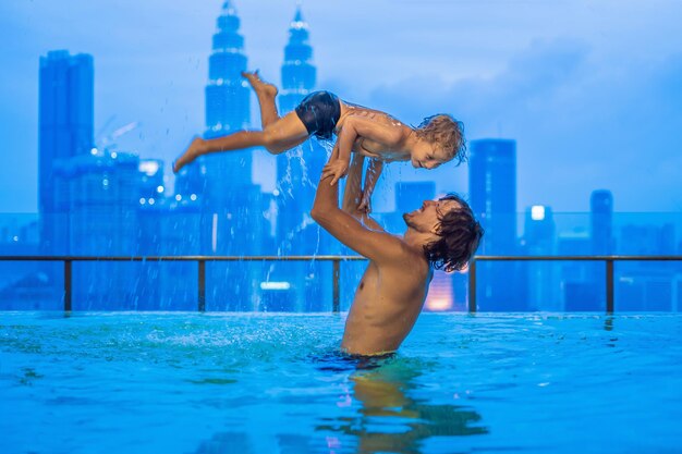 Pai e filho na piscina ao ar livre com vista da cidade no céu azul