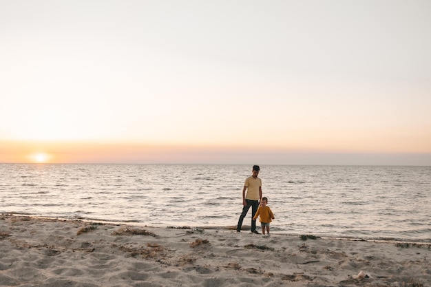 pai e filho na praia ao pôr do sol