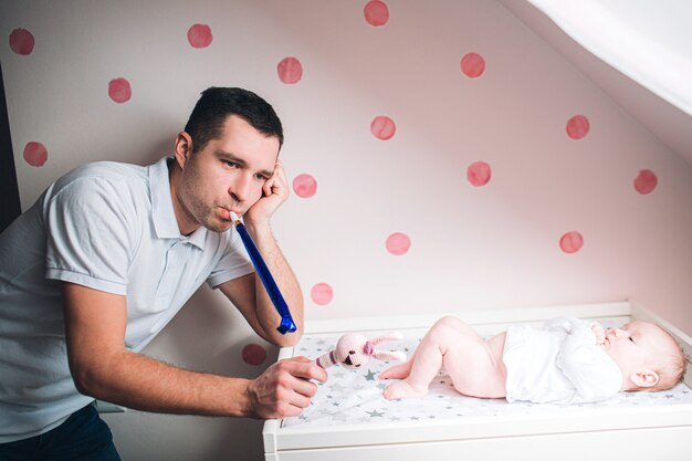 Pai e filho no berçário. O primeiro ano de vida. Incerteza e medo de uma criança. Papai não sabe o que fazer com a criança