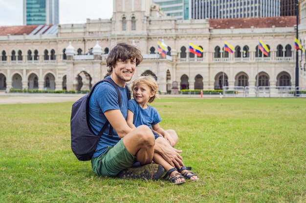 Pai e filho no fundo da Praça Merdeka e do Edifício Sultan Abdul Samad. Conceito de viajar com crianças