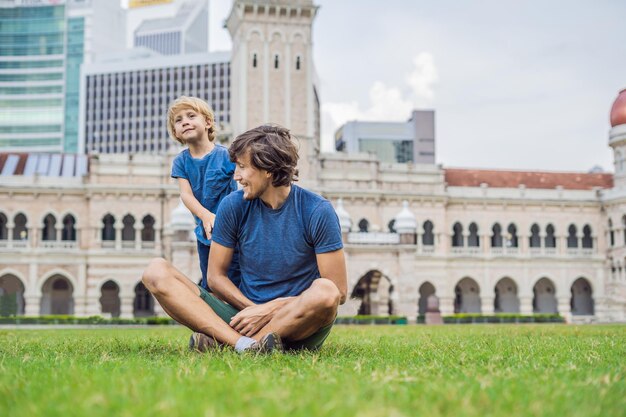 Pai e filho no fundo da Praça Merdeka e do Edifício Sultan Abdul Samad. Conceito de viajar com crianças