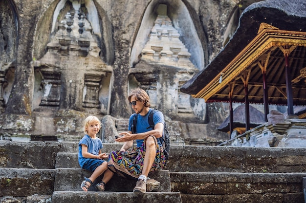 Pai e filho no fundo de Gunung Kawi. Antigo esculpido no templo de pedra com túmulos reais. Bali, Indonésia. Viajando com o conceito de crianças..