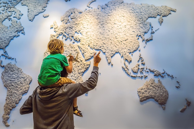 Pai e filho no fundo de um mapa do mundo com um avião nas mãos Conceito de viagem